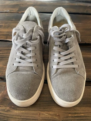 Gråa sneakers i mocka - Stilrena grå sneakers, Vagabond Paul i mocka med vita sulor och matchande grå skosnören. Klassisk låg modell med rund tå och enkel design som passar till det mesta. Perfekta för dig som gillar en clean och avslappnad look.
