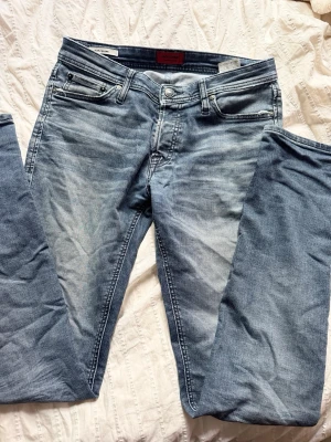 Slim fit jeans från Jack & Jones - Snygga ljusblå slim fit jeans från Jack & Jones, modell Glenn. Jeansen har klassisk femficksdesign och är tillverkade i mjukt denimtyg med lätt tvättad look. Perfekta för en avslappnad och trendig stil.