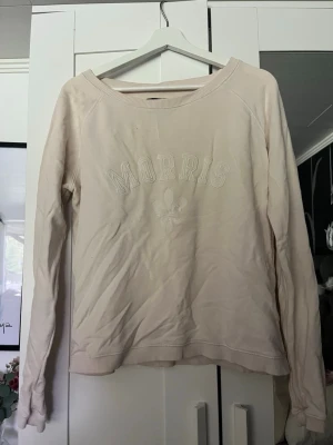 Beige sweatshirt från Morris - Snygg beige sweatshirt från Morris med broderad logga och text framtill. Tröjan har rund halsringning, långa ärmar och ribbade muddar vid ärmslut och nederkant. Perfekt för en avslappnad och stilren look.