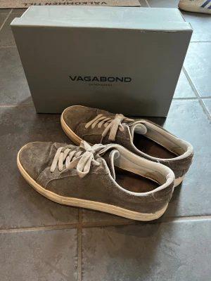 Gråa Vagabond sneakers i mocka - Snygga gråa sneakers från Vagabond i mjuk mocka med vita snören och vit sula. Klassisk låg modell som passar perfekt till jeans eller shorts. Skorna har en stilren design och är riktigt bekväma för vardagsbruk. Kan gå ner i pris vid snabb affär