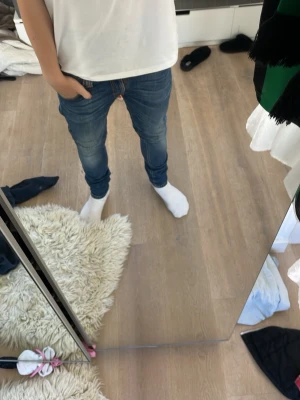 Blå slim fit jeans med stretch - Säljer ett par blå slim fit jeans med tvättade detaljer. Jeansen har klassisk femficksdesign, dragkedjegylf och smal passform som sitter tajt längs benen. Perfekta nästan hela tiden då man kan ha dom på fest och till jobbet