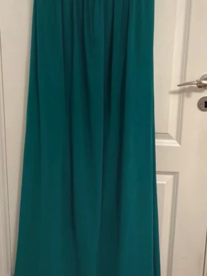 Turkos långklänning med paljettdetaljer - Snygg turkos långklänning med axelband och vadderad, draperad överdel. Sidorna har paljettdetaljer som ger extra bling. Kjolen faller mjukt och klänningen har en elegant, feminin siluett. Perfekt för speciella tillfällen!