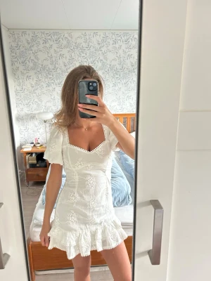 Vit kort klänning från Nelly med volang och broderi - Säljer denna superfina vita klänning från Nelly som är helt slutsåld! Storlek 34, helt oanvänd. Passar perfekt som studnetklänning💕👏🏼 