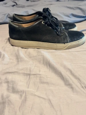 Svarta sneakers från Lanvin - Svarta sneakers från Lanvin med vit sula och klassisk snörning. Skorna har en stilren design med rund tå och är tillverkade i skinn. Perfekta för dig som gillar en clean och tidlös look.