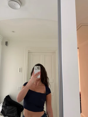 Mörkblå croppad topp - Snygg mörkblå croppad topp med korta ärmar och fyrkantig ringning. Perfekt till jeans eller kjol för en trendig look. Tunn och mjuk i materialet, sitter tight och framhäver midjan.