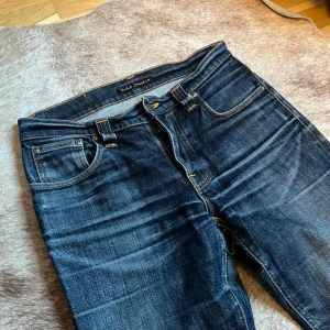 Nudie Grim Tim - Jävligt feta Grim Tims i storlek 31/34 fast passar W32. Riktigt fina fades och original distressing. Passformen är slim. Finns en lagning vid skrevet. Just dessa par jeans är en äldre Grim Tim modell då ”bälte hållarna” är bredare och backtaben är i glansig läder. Skriv vid funderingar kring jeansen eller priset. Skickar alltid inom 24 timmar. 
