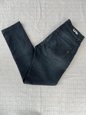 Svarta Dondup jeans, storlek 30 - Svarta Dondup jeans med schyssta fades i modellen Konor Skinny fit Inga defekter  Mått: Längd: 103 cm 1/2 midja: 39 cm Lårbredd: 26cm Benöppning: 16 cm  Hör av er vid frågor!