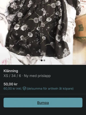 Svart blommig kortklänning XS - Svart kortklänning med vitt maskrosmönster. Klänningen har lång ärm och en luftig passform, perfekt för dig som gillar en söt och enkel stil. Tillverkad i ett lätt material som känns skönt mot huden.