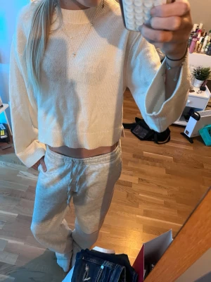 Beige cropped stickad tröja - Mysig beige stickad tröja med croppad passform och breda ärmar. Perfekt för chill dagar hemma. Tröjan har ribbade detaljer vid halsen och nederkanten. Materialet känns mjukt och bekvämt mot huden.