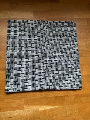 Svartvit kuddfodral med rutmönster 50x50 - Säljer en svartvit kuddfodral med grafiskt rutmönster. Tyget är rektangulärt och har ett stilrent, modernt uttryck med täta linjer i rutorna.