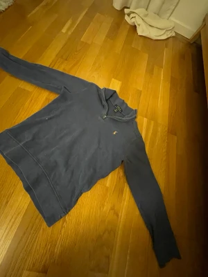 Mörkblå tröja från Polo Ralph Lauren - Mörkblå långärmad tröja från Polo Ralph Lauren med klassisk broderad logga på bröstet. Tröjan har halv dragkedja vid halsen och är tillverkad i mjukt bomullsmaterial. Perfekt för en avslappnad och stilren look.