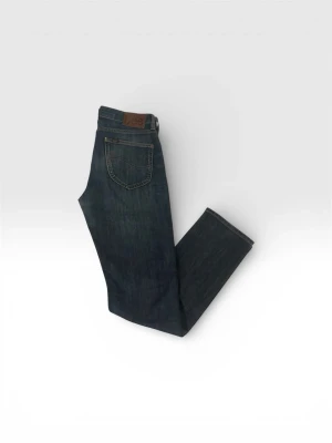 Mörkblå jeans från Lee - Snygga mörkblå jeans från Lee med klassisk femficksdesign och läderpatch bak i midjan. Jeansen har raka ben och är tillverkade i slitstark denim. Perfekta för en avslappnad och stilren look.