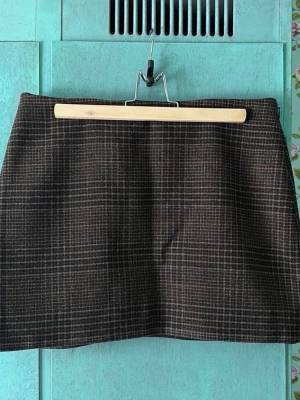 Brun rutig kortkjol i ullmix - Snygg brun rutig kortkjol med klassiskt mönster. Kjolen har en rak passform. Storlek 40. Helt ny med prislappar kvar. Det går bra att betala med Swish, köpare står för frakt.