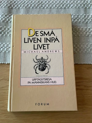 De små liven inpå livet - En beige inbunden bok med titeln 'De små liven inpå livet' av Michael Andrews. Undertitel: Upptäcktsresa på människans hud. Omslaget har en illustration av ett mikroskopiskt djur och tydlig svart text. Boken är på svenska och utgiven av Forum.
