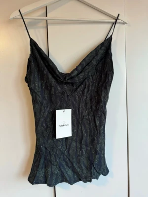 Nytt svart linne topp. Soft Rebels. S. NWT - Snygg svart linnetopp från Soft Rebels med tunna axelband och grönt mönster. Viskos. Toppen har en lätt draperad halsringning och sitter figurnära. Perfekt att styla med jeans eller kjol för en trendig look. Oanvänt. Storlek S. Lappen kvar. Finns inget att anmärka på. NWT.