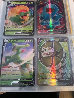 Pokémon V-kort samling i pärm - Fyra Pokémon V-kort i plastficka: Appletun V, Drifblim V, Virizion V och Sandaconda V. Alla korten har holografisk finish och färgstarka illustrationer. Perfekt för samlare eller Pokémon-fans som vill utöka sin samling.