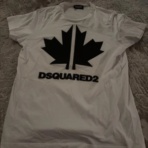 Vit t-shirt med svart löv från Dsquared2 - Det är en fin dsquared tröja med storlek 14 år. Tröjan är tryckt med plastisol tryck alltså är löven och texten över tröjans tyg som gör t shirten unik och fin. Det står Sport edt.04. Tröjan är 100% autentisk, köpt från kids brand store. Priset kan diskuteras👍