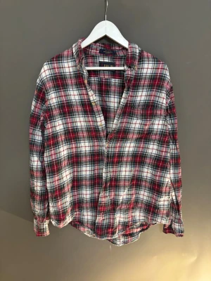 Rutig skjorta från Arrow i bomull - Säljer en klassisk rutig skjorta från Arrow i storlek L. Skjortan har en schysst färgkombo med rött, vitt och mörkgrönt, långa ärmar och knappar framtill. Materialet är mjuk 100% bomull, perfekt för chill dagar. Passformen är normal och mönstret är riktigt tidlöst.