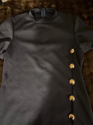 Klänning  - En marinblå klänning med knappar och slits 