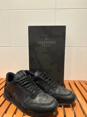 Svarta sneakers från Valentino Garavani - Snygga svarta sneakers från Valentino.  Perfekta för dig som gillar exklusiv streetwear och vill ha något unikt på fötterna. Inte nytt skick men ganska okej skulle jag säga, dessa skor har mycket kvar att ge. De är i storlek 42 men passar även mig som har 43. Nypris runt 5000kr, mitt pris 1999kr. Kvitto låda och två dustbags fås med. Kan gå ner i pris vid snabb affär. Vid frågor eller funderingar skriv till mig!