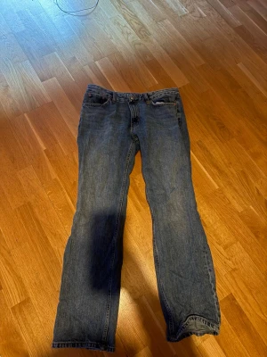 Blå low waisted bootcut jeans - Säljer ett par blå jeans low waisted bootcut. Jeansen har en klassisk look med normal midja och är tillverkade i denim. Perfekta för dig som gillar en tidlös stil och vill ha ett par jeans som funkar till det mesta. Passar M/L