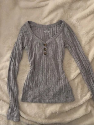 vintage yk2 tajt hollister topp - vintage grå tajt figurnära ribbad tröja från hollister. bruna knappar och djup urringning. stl XS och jätte fint skick!💕