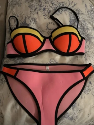 Rosa och orange bikini med svarta kanter - Snygg bikini i rosa och orange med svarta kontrastkanter. Jättefin har använt vara en gång riktigt priset är 650kr