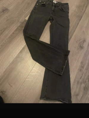 Svarta bootcut jeans - Säljer ett par svarta bootcut jeans med klassisk femficksdesign och normal midja. Jeansen har en lätt utsvängd passform nedtill och är tillverkade i denim. Perfekta för dig som gillar en avslappnad men ändå trendig look.