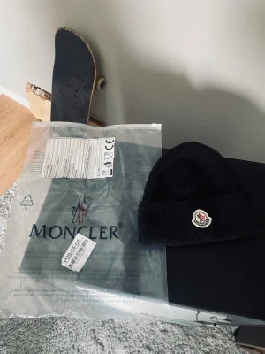 Svart Moncler mössa med logotyp - Säljer en svart ribbstickad mössa från Moncler med den klassiska Moncler-logotypen framtill. Mössan.