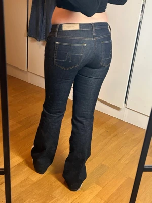 Lågmidjade bootcut jeans lowwaist lowrise flare - Marinblå jeans med snygg rhinestone detalj på bakfickorna. från Zara, många år gamla, men knappt använda så i superfint skick. 36 enligt lapp men små i storleken och passar 34 bättre. Försmå för mig som brukar ha 36. Innerbenslängd: 80 midjemått: 39. Köp sker via köp nu, jag postar inom 24h. Kvar tills markerad såld 