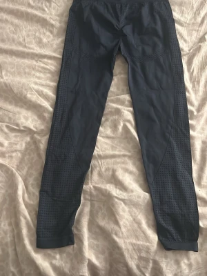 Blå sportiga leggings med meshdetaljer - Säljer ett par blåa leggings med snygga meshdetaljer längs benen. De har en tight passform och bred mudd i midjan för extra komfort. Perfekta för träning eller chill. Materialet är stretchigt och andas bra.