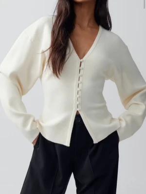 Figursydd kofta gina tricot  - Stilren krämvit cardigan med djup V-ringning och dekorativa knappar framtill. Tröjan har lång ärm och rak passform, perfekt att matcha med både jeans och kostymbyxor. Mjuk och skön kvalitet som känns lyxig.
