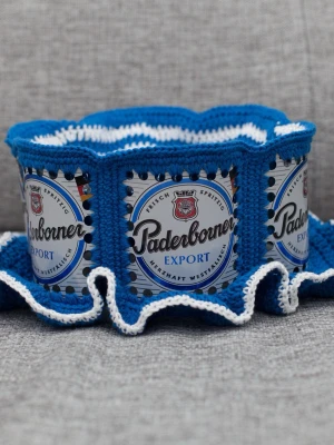 Virkad ölhatt Paderborner - Unik virkad ölhatt med Paderborner.  Virkad i 100% bomull. Passar upp till 57cm.  Vissa burkar kan ha mindre repor eller bucklor, vilket tyvärr kan uppstå under tillverkningen av hattarna. Insidan av burkarna slipas efter hålen tagits för att undvika vassa kanter. Därför kan det ibland finnas lite slipmärken, men det är inget som stör eftersom det är på insidan av hattarna.  Färger kan variera något beroende på skärminställningar.