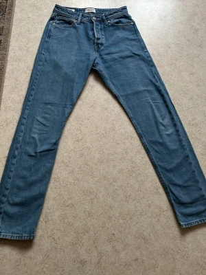 Blå raka jeans från Jack&jones - Klassiska blå jeans från Jack&jones med rak passform och fem fickor. Jeansen har normal midja, knappgylf och är tillverkade i slitstarkt denimtyg. Perfekta för en avslappnad och tidlös stil. Modellen heter chris och storleken är W29 L32
