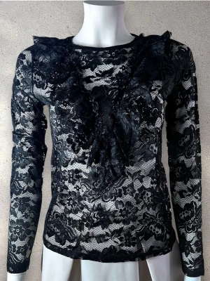 Svart spetsblus med volangdetaljer - Snygg svart blus i transparent spets med blommigt mönster och volangdetaljer framtill. Långärmad modell med rund halsringning. Perfekt för dig som vill ha en trendig och elegant look. #ginatricot PS: Köpt på Gina Tricot, men är utan etikett.