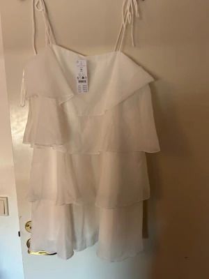 Vit volangklänning - Vit kort klänning med volanger i storlek 36(passar större). Perfekt till studenten eller till sommaren. Aldrig använd🌸