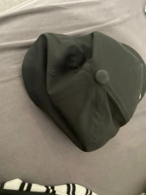 Svart keps från Hugo Boss - Snygg svart keps från Hugo Boss med en stor guldfärgad metallbricka framtill där det står BOSS HUGO BOSS. Klassisk böjd skärm och justerbar baksida. Tillverkad i bomullsmaterial för en bekväm känsla. 