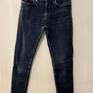Mörkblå skinny jeans-Tiger Of Sweden  - Säljer ett par mörkblå skinny jeans med klassisk femficksdesign och dragkedjegylf. Jeansen har en smal passform och subtila slitningar för en modern look. Perfekta till vardags och lätta att matcha med olika stilar.