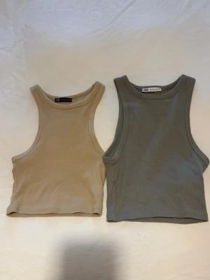Paketpris Beige och grå ribbade linnetoppar Zara - Två ribbade linnetoppar från Zara, en i beige och en i grått. Båda är croppade och har breda axelband samt rundad halsringning. Perfekta att matcha med jeans eller kjol för en chill look. Materialet är mjukt och stretchigt, vilket gör dem bekväma att bära.