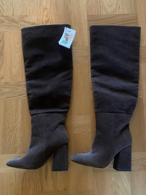 Bruna höga mockastövlar  - Bruna stövlar i mocka med hög klack från Pimkie. Helt oanvända med lappen kvar. Storlek 36. Köparen står frakten. 