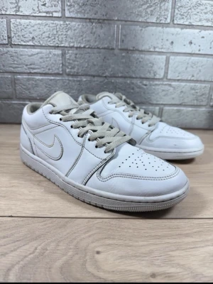 Nike Air Jordan 1 Low vita sneakers Storlek 41 - Säljer ett par klassiska Nike Air Jordan 1 Low sneakers i helvitt läder med grå detaljer och broderad Air Jordan-logga på hälen. Skorna har perforerad tåbox, vita sidor och grå snören. Perfekta för dig som gillar stilrena och tidlösa sneakers. Storlek 41 och innersulans mått 26cm.  Skorna är orginella, snygga och mycket bekväma. De är i väldigt bra skick vilket syns på bilderna.  Pris kan diskuteras , hör av dig! 🤙 