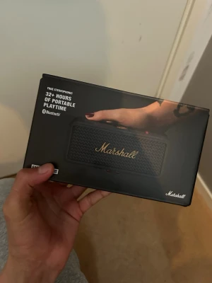 Marshall Emberton II trådlös högtalare - Marshall Emberton II är en kompakt och portabel trådlös högtalare med klassisk svart design och guldlogga. Den har Bluetooth, över 32 timmars batteritid och levererar kraftfullt stereoljud. Perfekt för att ta med sig överallt och spela musik trådlöst.