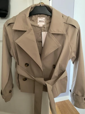 Trenchcoat Gina o - Säljer min helt nya trenchcoat från Gina Young. Aldrig använd och med prislapp på. Rymlig storlek, passar även XS. 