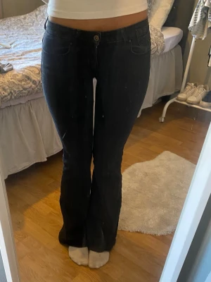 Svarta bootcut jeans med hög midja - Snygga svarta bootcut jeans med låg midja och klassisk femficksdesign. Jeansen har en smal passform upptill och utsvängda ben nertill. Perfekta för dig som gillar en trendig och tidlös look.