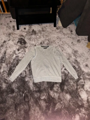 Ljusgrå sweatshirt från g-star - En stilren ljusgrå sweatshirt med rund hals och långa ärmar. Tröjan har ribbade muddar vid ärmslut och nederkant samt en diskret ficka bak. Perfekt för en avslappnad look och enkel att matcha med andra plagg.