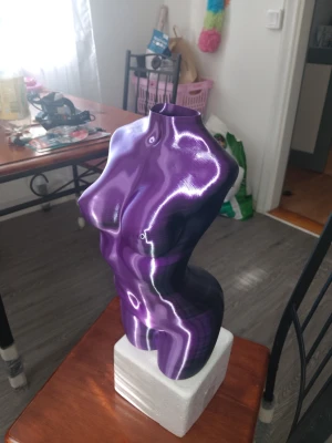 Lila och svar 40cm hög kvinnlig bystskulptur/ Vas  - Unik 40cm hög bystskulptur / vas i form av en kvinnlig torso med blanka, vågiga mönster i lila och svart. Skulpturen står på en vit sockel och har en modern, konstnärlig design som sticker ut i rummet. Perfekt som dekoration eller konstobjekt.