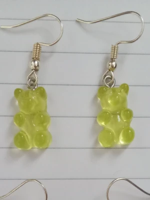 Lime björn örhängen  - Säljer ett par unika örhängen med lime gummibjörns-hängen i plast. Örhängena har krokar i metall och är knappt använda. 