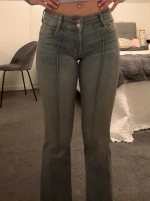 Ljusblå bootcut jeans med låg midja - Säljer ett par blåa bootcut jeans med låg midja och markerad söm framtill. Jeansen har dubbla knappar, bälteshällor och klassiska fickor fram och bak. Snygg passform som framhäver benen och passar perfekt till dig som gillar bekväma men trendiga jeans!