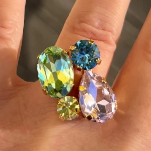 Mixed sized ring Rainbow guldpläterad kristall - Mixed sizes ring i guldpläterad mässing med päron, oval och chaton kristaller 10x14mm samt ss39 8mm och ss29 6mm. Färg Rainbow, Light Rose, Cool Blue, Jonquil och Chrysolite. Ställbar storlek. Sista bilderna visar andra färger och modeller.  Jag skickar endast spårbart, samfraktar. Fast pris. Besök gärna mina övriga annonser.  Till mina smycken använder jag kristaller från Preciosa, Aurora och Swarowski.