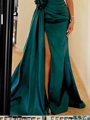 Mörkgrön långklänning med slits - Elegant mörkgrön långklänning med hög slits och draperad midja. Använd endast en gång och passar 34/36